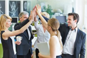Glückliches Business Team macht High Five mit den Händen im Büro